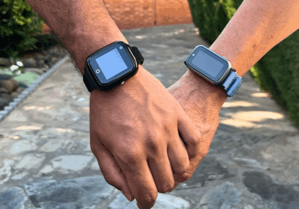 Två personer håller hand på promenad på stenlagd gång. Båda händerna bär Sensorems trygghetslarm.